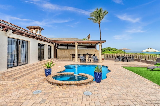 view of pool featuring a water view, an in ground hot tub, and a patio