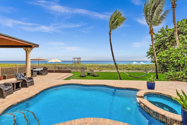 view of pool featuring a water view, an in ground hot tub, a patio, and a lawn