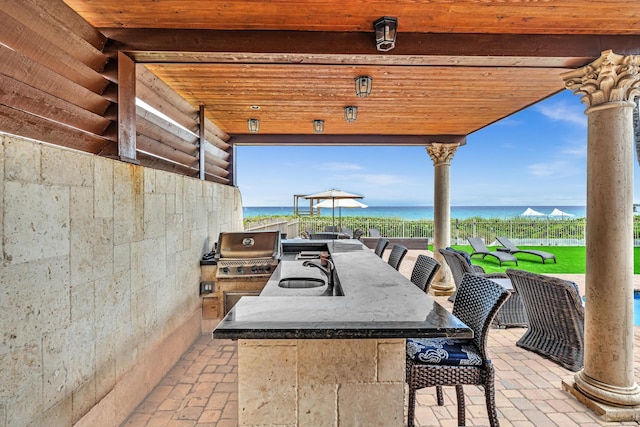 view of patio / terrace with a water view, area for grilling, sink, and grilling area