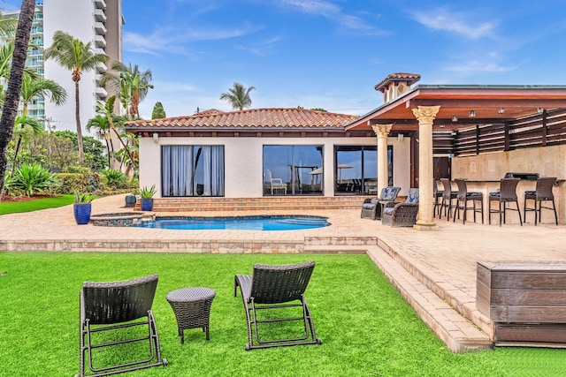 back of house featuring a bar, a patio area, and a lawn