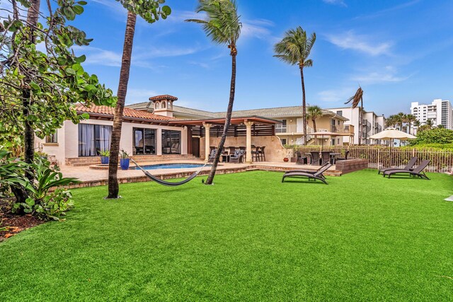 rear view of house featuring a pool, a lawn, and a patio area