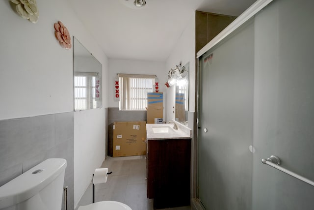 bathroom with tile walls, vanity, an enclosed shower, toilet, and tile patterned floors