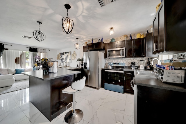 kitchen with hanging light fixtures, sink, dark brown cabinets, appliances with stainless steel finishes, and a kitchen breakfast bar