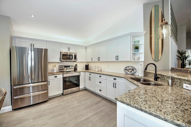 kitchen with white cabinets, sink, stainless steel appliances, and kitchen peninsula