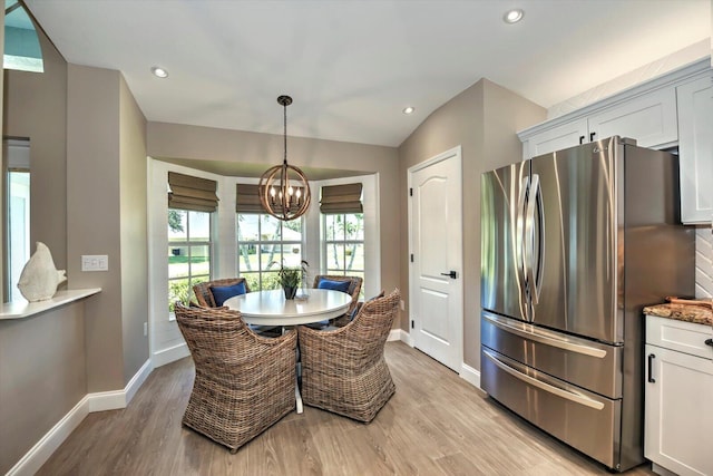 dining area featuring lofted ceiling, light hardwood / wood-style floors, and an inviting chandelier