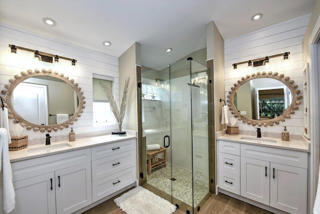 bathroom with wooden walls, wood-type flooring, vanity, and a shower with door