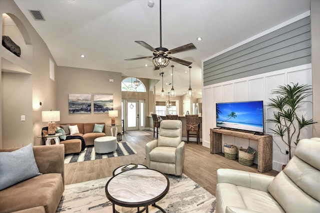 living room featuring light hardwood / wood-style flooring, a towering ceiling, and ceiling fan