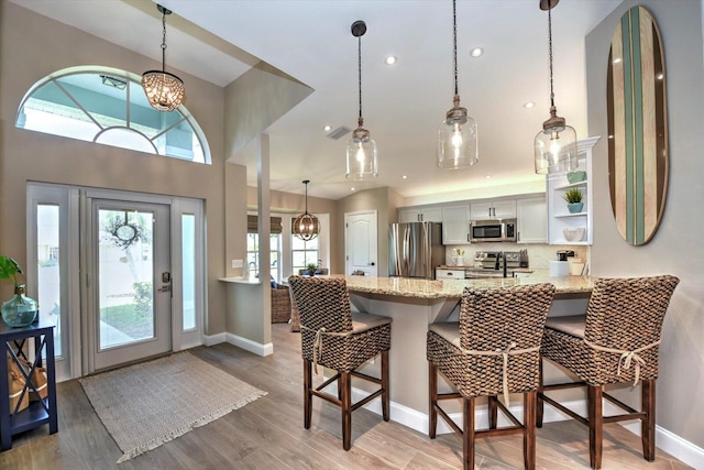 kitchen featuring white cabinets, appliances with stainless steel finishes, a breakfast bar, and a wealth of natural light