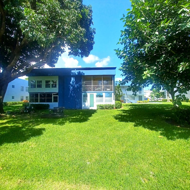 back of house featuring a lawn and a sunroom