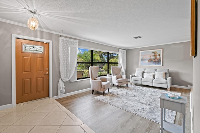 living room featuring light hardwood / wood-style flooring, a textured ceiling, and ornamental molding