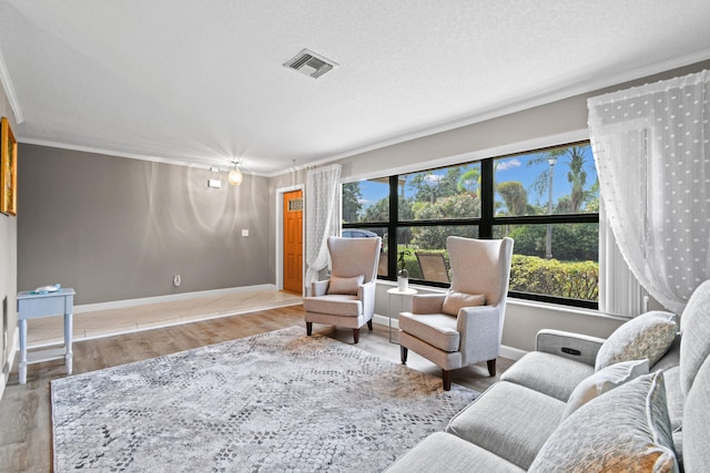 living room with crown molding, light hardwood / wood-style flooring, and a textured ceiling