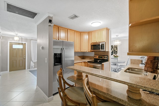 kitchen featuring kitchen peninsula, appliances with stainless steel finishes, light brown cabinetry, sink, and a breakfast bar area