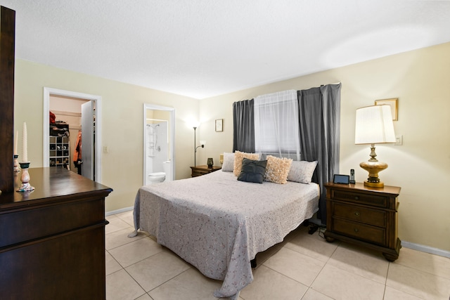 tiled bedroom with a spacious closet, a closet, and ensuite bathroom