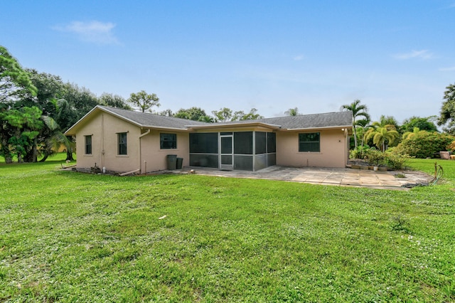 back of property featuring a sunroom, a patio area, and a lawn