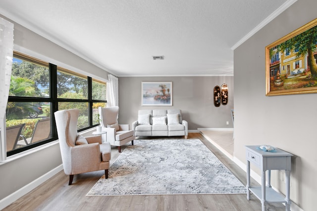 living room with ornamental molding, a textured ceiling, and light hardwood / wood-style flooring