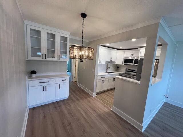 kitchen featuring hanging light fixtures, sink, white cabinetry, hardwood / wood-style flooring, and stainless steel appliances