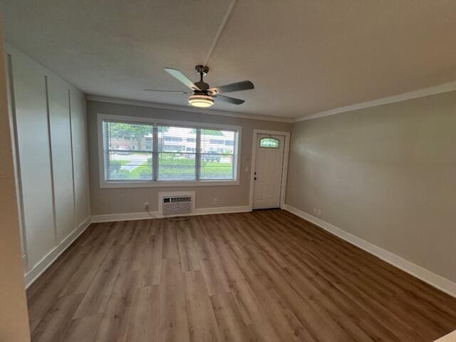 interior space with light hardwood / wood-style flooring, ceiling fan, ornamental molding, and a wall mounted air conditioner