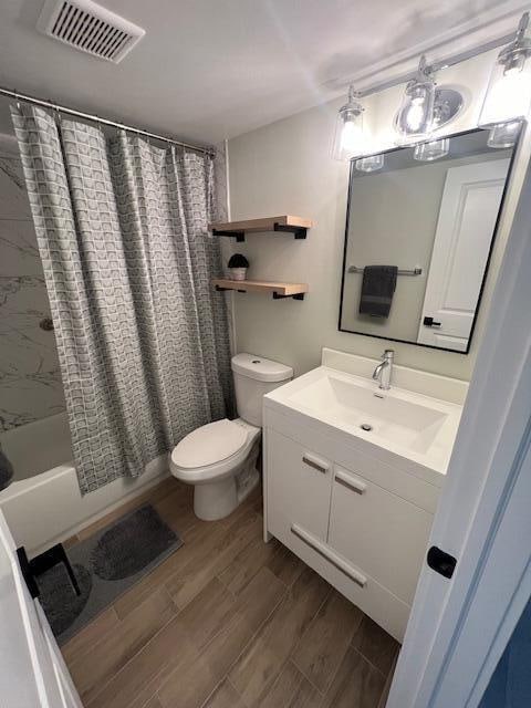 full bathroom featuring wood-type flooring, vanity, toilet, and shower / bath combo