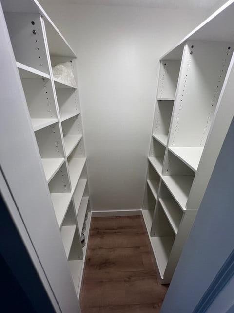 walk in closet with dark wood-type flooring