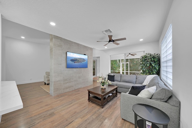 living room with ceiling fan, wood-type flooring, and a textured ceiling