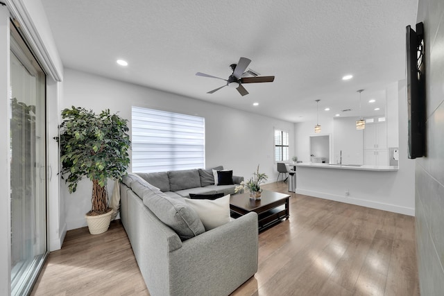 living room featuring a textured ceiling, light hardwood / wood-style floors, and ceiling fan