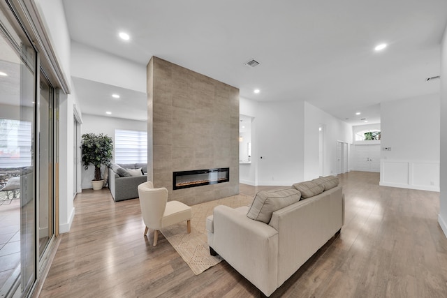 living room featuring a tile fireplace and light wood-type flooring