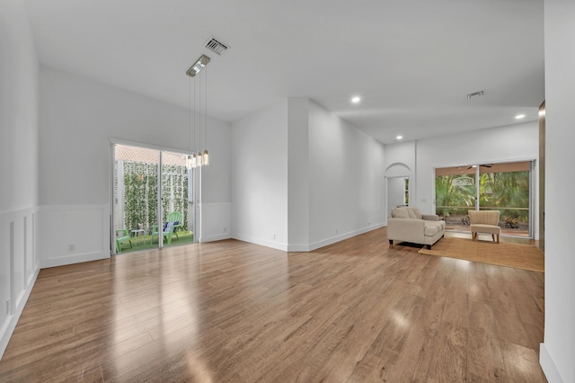 unfurnished living room featuring a notable chandelier, a healthy amount of sunlight, and light hardwood / wood-style flooring