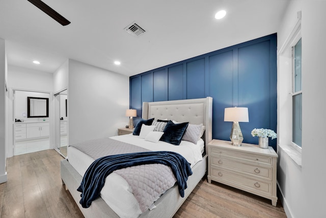 bedroom featuring ceiling fan, light wood-type flooring, connected bathroom, and a closet