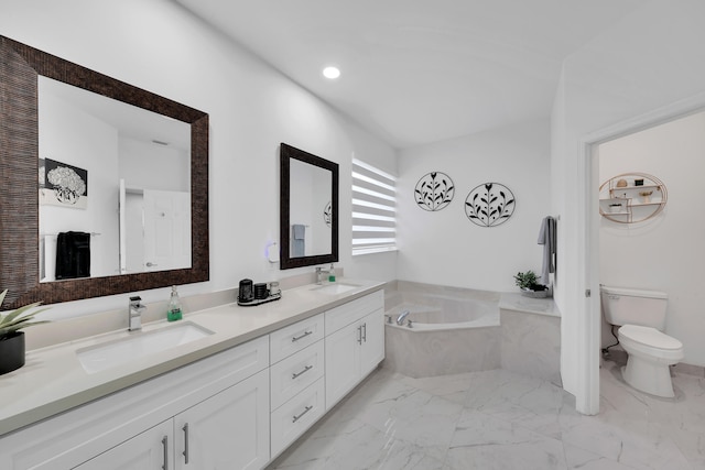 bathroom featuring vanity, a relaxing tiled tub, and toilet