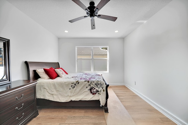 bedroom featuring ceiling fan, light wood-type flooring, and a textured ceiling