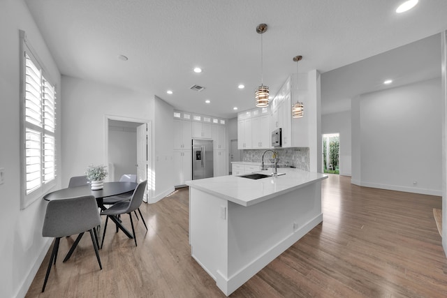 kitchen with sink, hanging light fixtures, stainless steel appliances, kitchen peninsula, and white cabinets