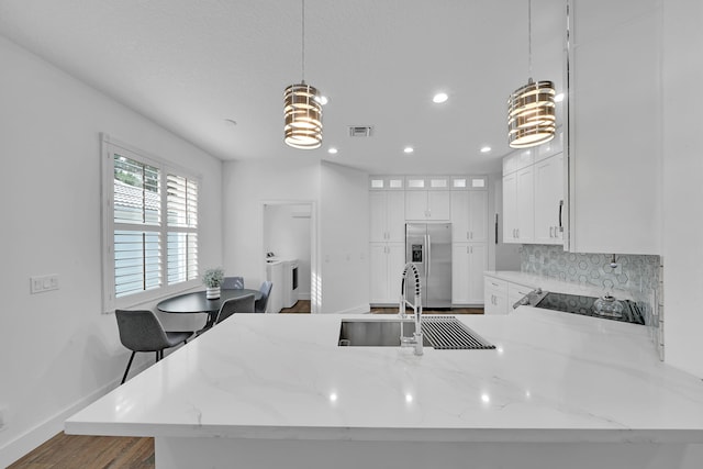 kitchen with kitchen peninsula, sink, decorative light fixtures, stainless steel fridge with ice dispenser, and white cabinetry