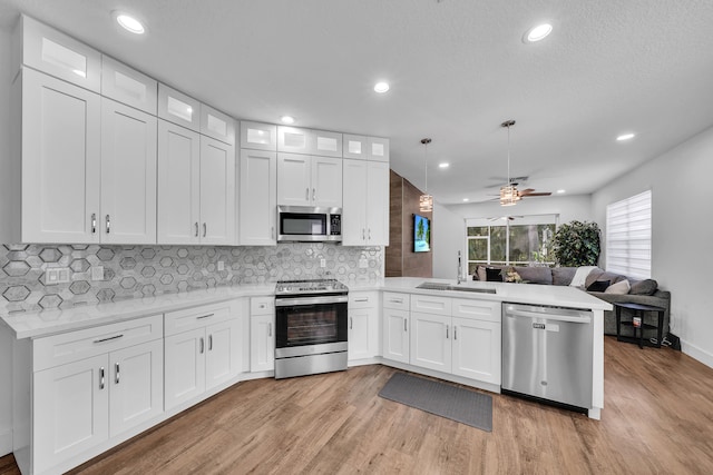 kitchen with white cabinets, decorative light fixtures, kitchen peninsula, and stainless steel appliances