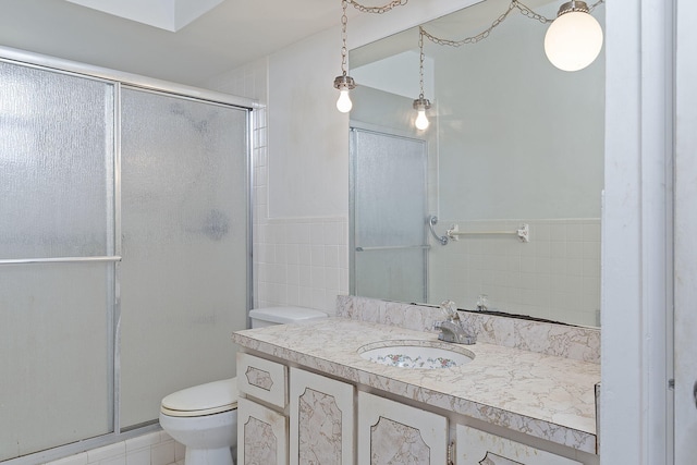 bathroom with vanity, tile walls, toilet, and a shower with door