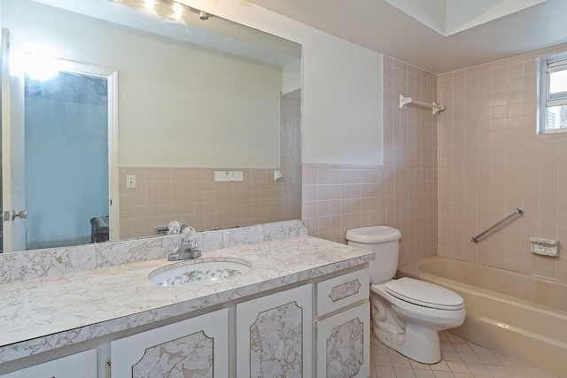 full bathroom with tile walls, tile patterned flooring, vanity, tiled shower / bath, and toilet