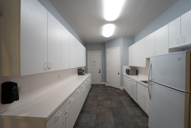 kitchen featuring white cabinets, a textured ceiling, and white appliances