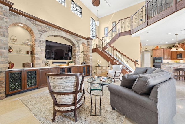 tiled living room with ceiling fan and a high ceiling