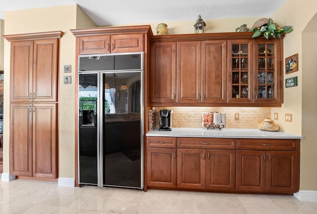 kitchen featuring black built in fridge, a textured ceiling, and backsplash