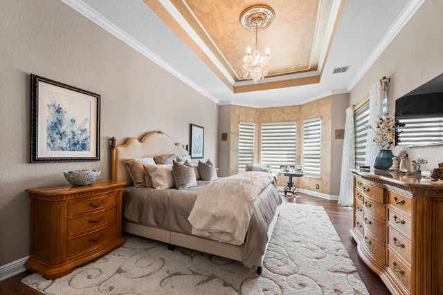 bedroom featuring dark wood-type flooring, a raised ceiling, ornamental molding, and a chandelier