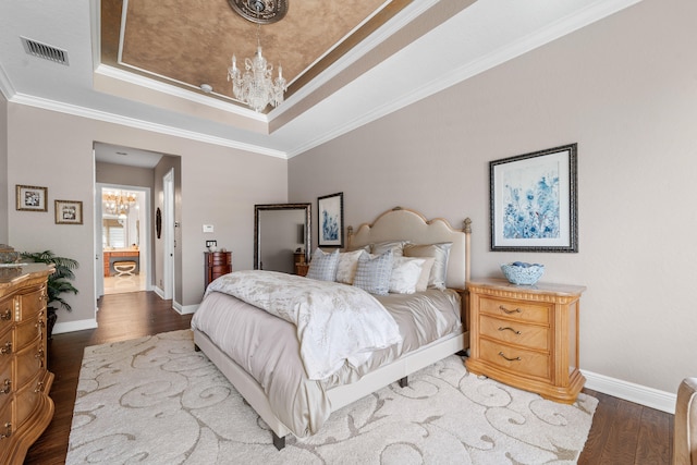 bedroom featuring a notable chandelier, hardwood / wood-style floors, a tray ceiling, and crown molding