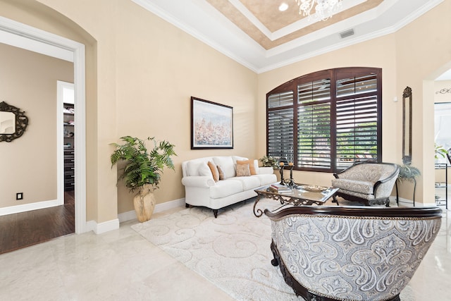 living room with ornamental molding, a tray ceiling, and a chandelier