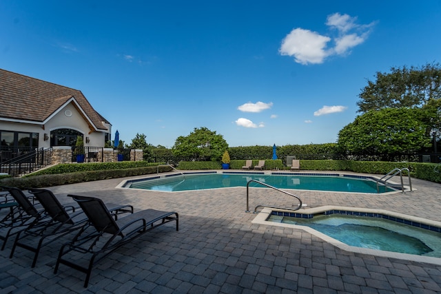 view of swimming pool with a hot tub and a patio area