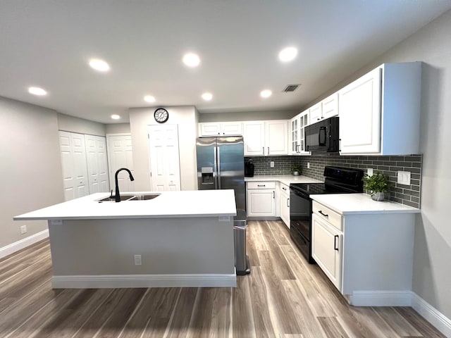 kitchen with a center island with sink, sink, black appliances, and white cabinets