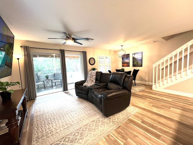 living room with ceiling fan with notable chandelier and hardwood / wood-style floors