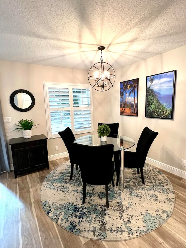 dining area featuring a textured ceiling, a chandelier, and wood-type flooring