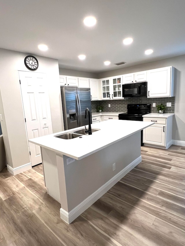 kitchen featuring white cabinetry, black appliances, light hardwood / wood-style flooring, and a kitchen island with sink