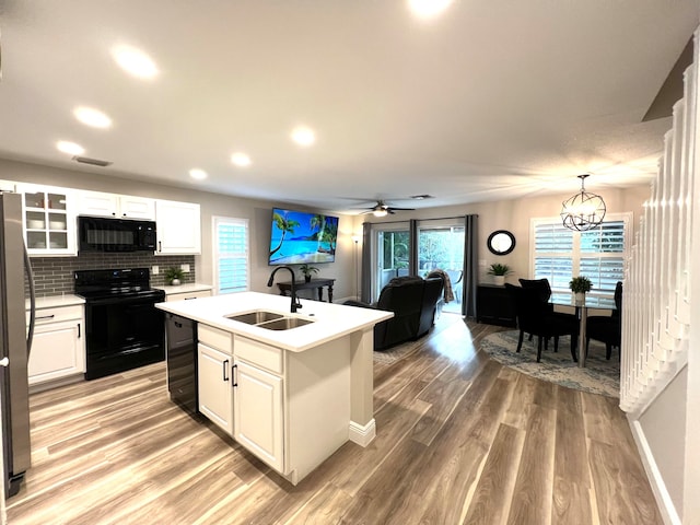 kitchen featuring sink, black appliances, a kitchen island with sink, and white cabinetry