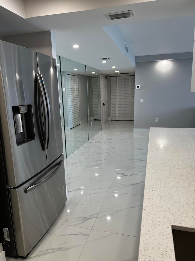 kitchen with light stone countertops and stainless steel fridge