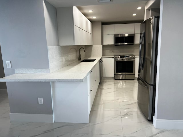 kitchen featuring light stone counters, stainless steel appliances, backsplash, and sink