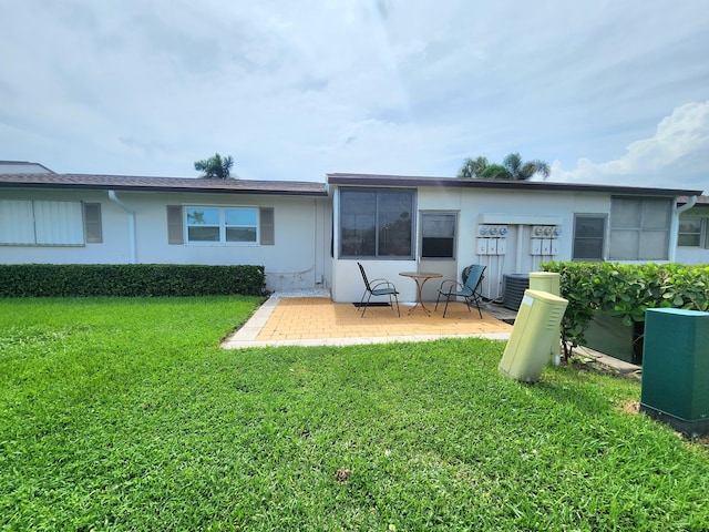 back of property with a lawn, central AC unit, and a patio area